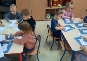 Dzieci malują farbami sylwety bałwanków