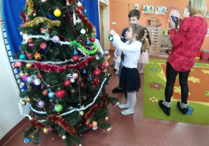 dzieci wieszają świąteczne ozdoby