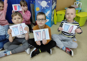 dzieci pokazują rysunki kubeczka i szczoteczki