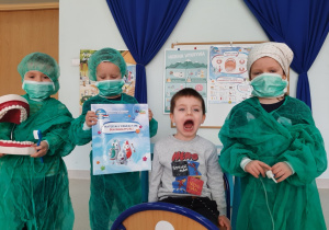 czworo dzieci pokazuje plakat promujący mycie zębów