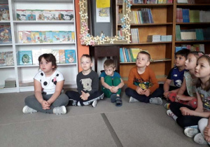 dzieci słuchają zasad korzystania z biblioteki siedząc na dywanie