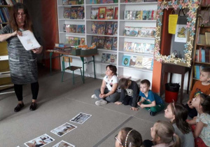 dzieci słuchają zasad korzystania z biblioteki siedząc na dywanie
