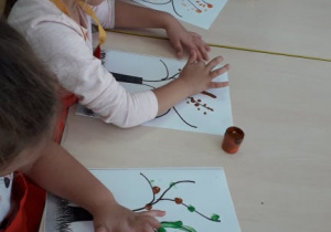 dzieci malują paluszkami listki jesiennego drzewa