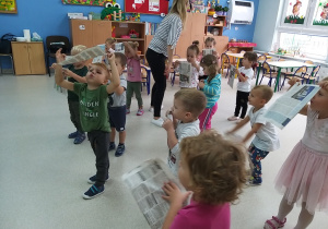 dzieci dmuchają w gazetę robiąc wietrzyk