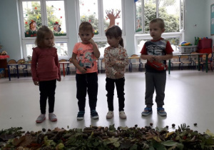czworo dzieci segreguje dary jesieni zanosząc je na stoliczki
