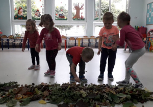 czworo dzieci segreguje dary jesieni zanosząc je na stoliczki