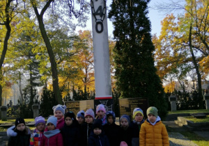 Dzieci stoją pod pomnikiem ofiar Katynia.