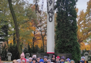 Dzieci stoją pod pomnikiem ofiar Katynia.