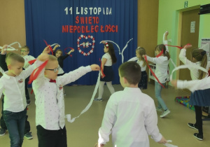 Taniec grupy Motylki z biało-czerwonymi paskami bibuły do piosenki pt. "Jesteśmy Polakami"