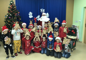 Przedszkolaki prezentują swoje prezenty i pozują do zdjęcia z Mikołajem