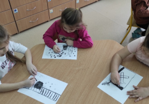 Dzieci rysują węglem na białych kartonach