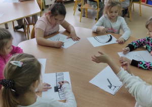 Dzieci rysują węglem na białych kartonach