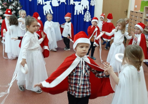 Przedszkolaki tańczą i śpiewają w strojach aniołków i Mikołajów