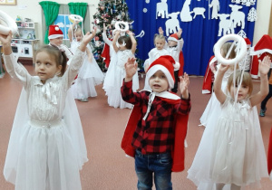 Przedszkolaki tańczą i śpiewają w strojach aniołków i Mikołajów