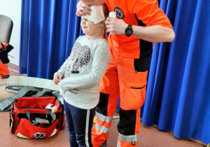 Ratownik medyczny bandażuje dziewczynce głowę