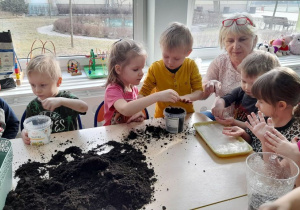 Dzieci wsypują nasionka do pojemników