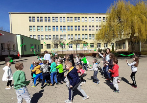 Dzieci tańczą z paskami bibuły w kolorach symbolizujących Ziemię i wodę
