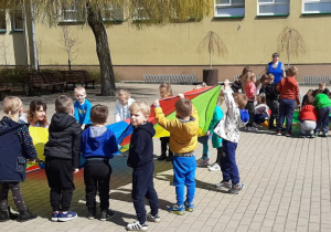 Dzieci biorą udział w zabawie z chustą animacyjną