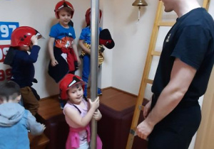 Dziewczynka zjeżdża rurą strażacką w sali edukacyjnej "Ognik".