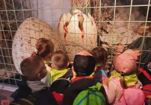 Dzieci oglądają dinozaura wykluwającego się z jaja