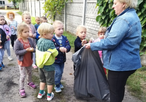 Przedszkolaki wrzucają śmieci do worka