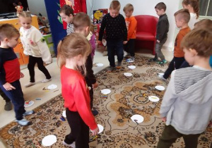 Dzieci poruszają się pomiędzy papierowym bombkami rozłożonymi na podłodze
