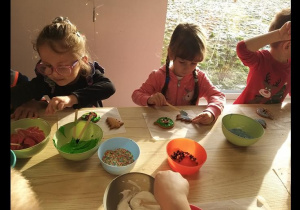 Dzieci ozdabiają upieczone pierniczki lukrem i słodyczami