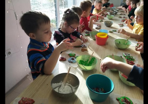 Dzieci ozdabiają upieczone pierniczki lukrem i słodyczami