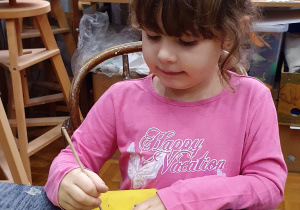 Dziewczynka rysuje wzorki patyczkiem na filiżance z gliny