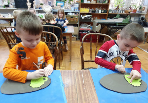 Chłopcy wycinają patyczkami filiżanki z gliny