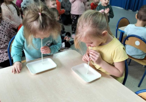 Przedszkolaki piją mleczko przez słomkę