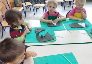 Dzieci wycinają kurkę z gliny