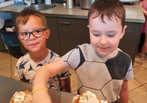 Chłopcy dekorują kolorową posypką desery lodowe.