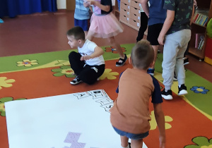 Dzieci szukają ukrytych w sali liter.