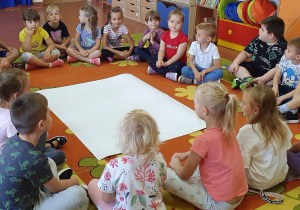 Przedszkolaki siedząc w kole na dywanie opowiadają o swoich marzeniach..