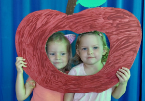 dziewczynki pozują do zdjęcia w jabłkowej fotobudce