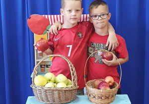 Chłopcy robią pamiątkowe zdjęcie przy straganie z jabłkami