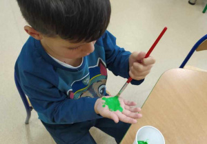 Chłopiec maluje rękę farbą