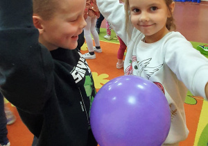 Dziewczynka z chłopcem tańczą z balonem przy muzyce
