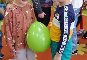 Dziewczynka z chłopcem tańczą z balonem przy muzyce
