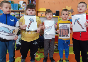 Chłopcy prezentują ilustracje narzędzi, którymi w pracy posługuje się górnik