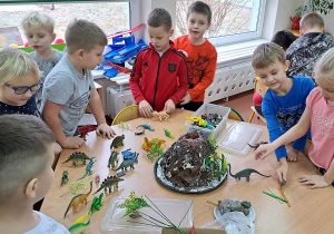 Dzieci bawią się dinozaurami przy wykonanym wcześniej wulkanie