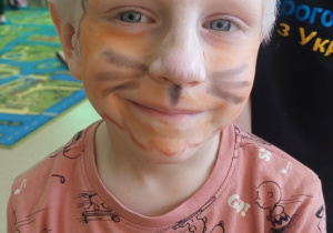 Chłopiec z pomalowaną twarzą kotka