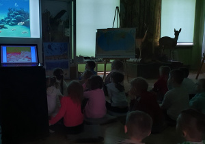 Dzieci oglądają prezentację multimedialną na temat morskich zwierząt żyjących ponad 150 lat temu na terenie Tomaszowa Maz.