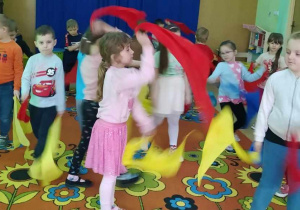 Dzieci tańczą z kolorowymi chustami do piosenki o wiośnie