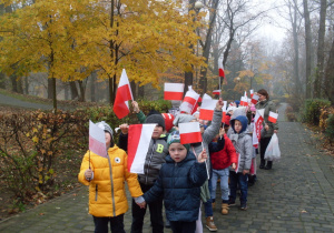 Dzieci idą z flagami w ręce.