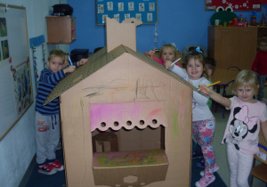 Dzieci kolorują tekturowy domek.