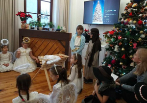 Dzieci w przebraniach jasełkowych śpiewają kolędę.