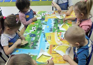 Dzieci malują farbą papierowe talerzyki.