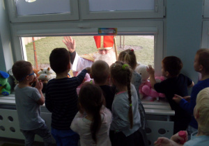Dzieci oglądaja przez okno Świetego Mikołaja.